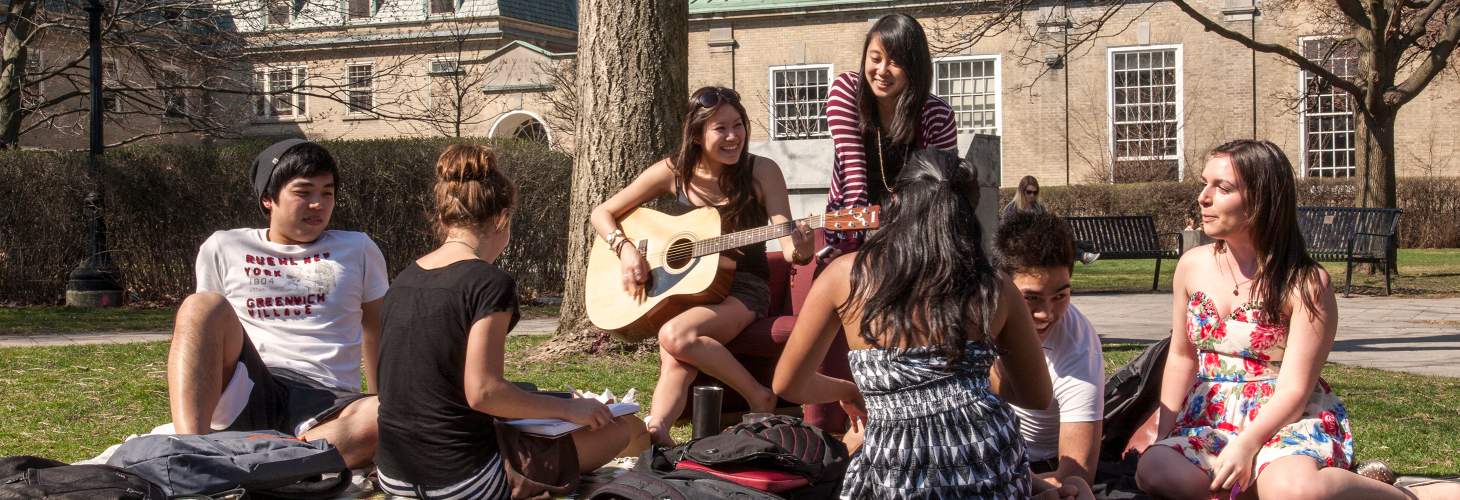 Students in group listening to woman playing guitar