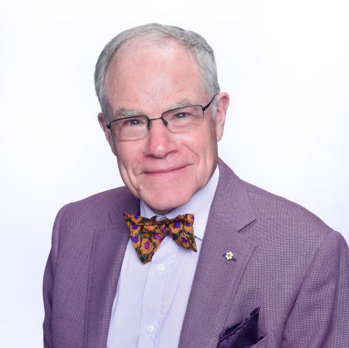 Portrait of an older white man with grey hair, glasses, and bow-tie