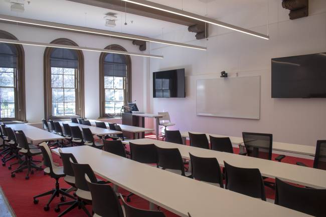 A multimedia classroom with rows of seating, multiple screens, and large windows