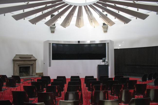 Circular conference room with large video display and geometric chandelier