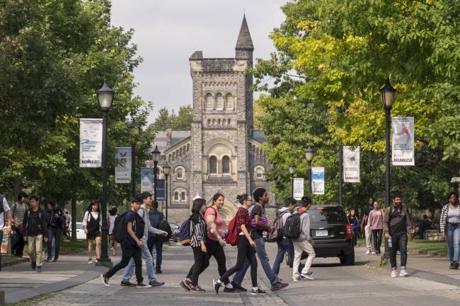 Group of student walking across front entrance of U of T with University College in the background