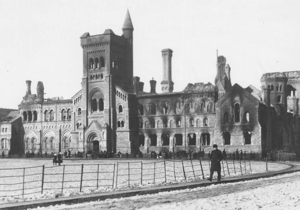 University College damaged by fire, with dozens of people and two horse-drawn carriages in front of the building