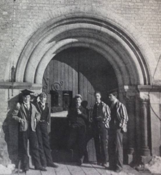 A young William Lyon Mackenzie King with four other young men, standing in front of arched doorway