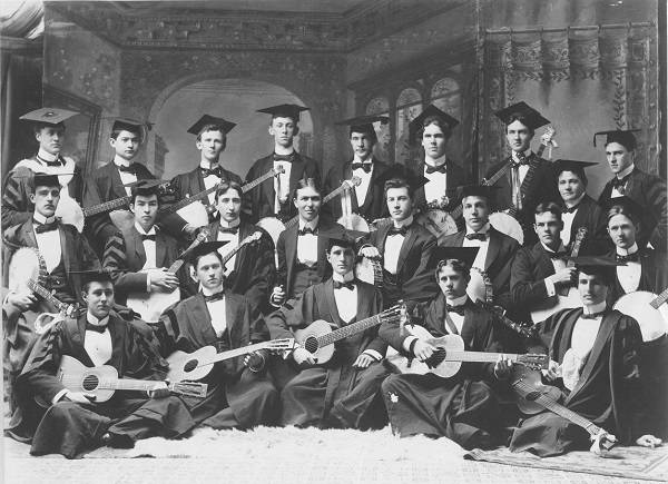 About 20 men, each holding a banjo or guitar, dressed in academic robes and mortarboards