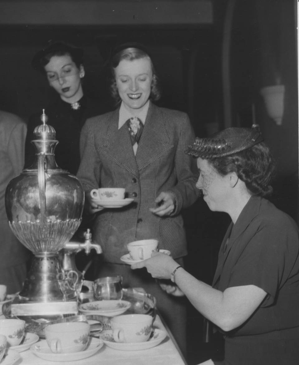 Woman serving tea from a samovar to two other women