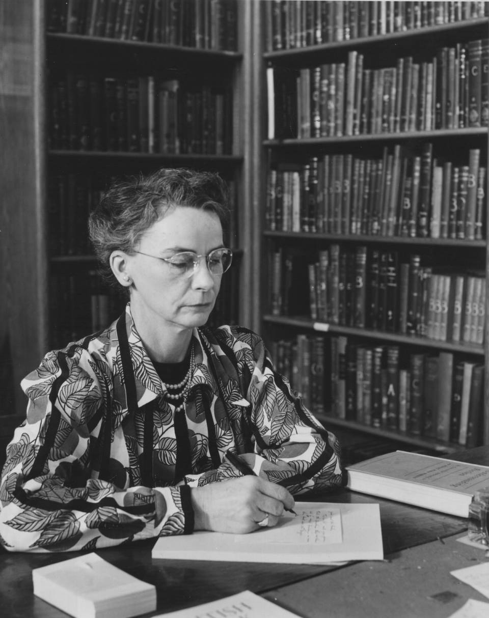 Margaret Hiltz working at desk, with shelves of books in the background