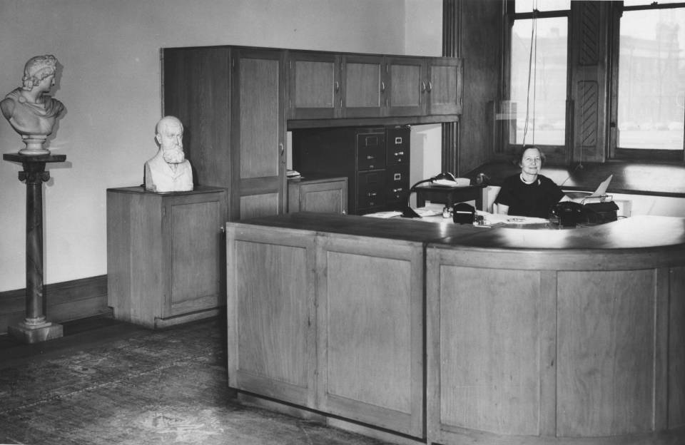 Woman seated behind large desk with counter