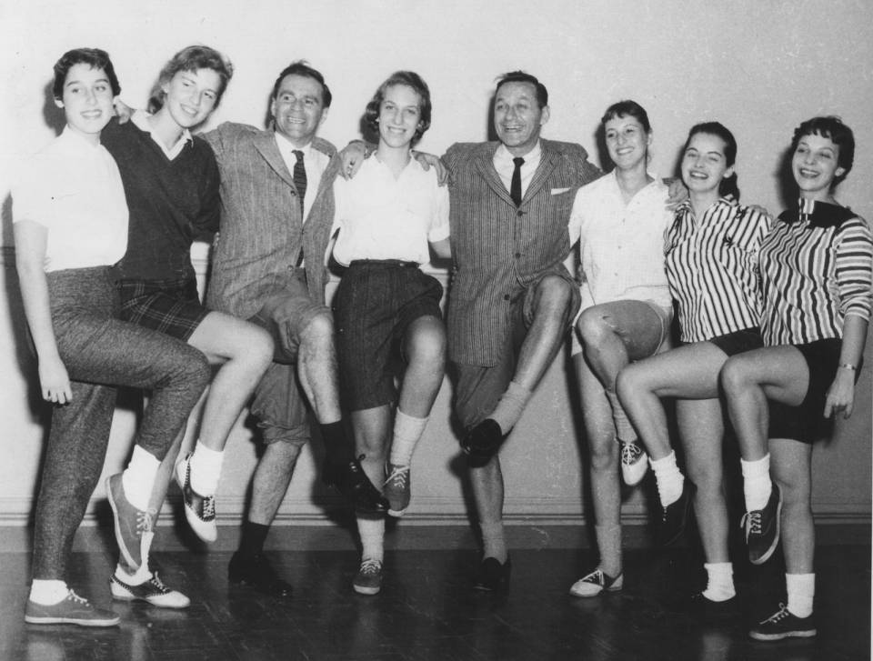 Johnny Wayne and Frank Shuster and six young women posing with one knee raised