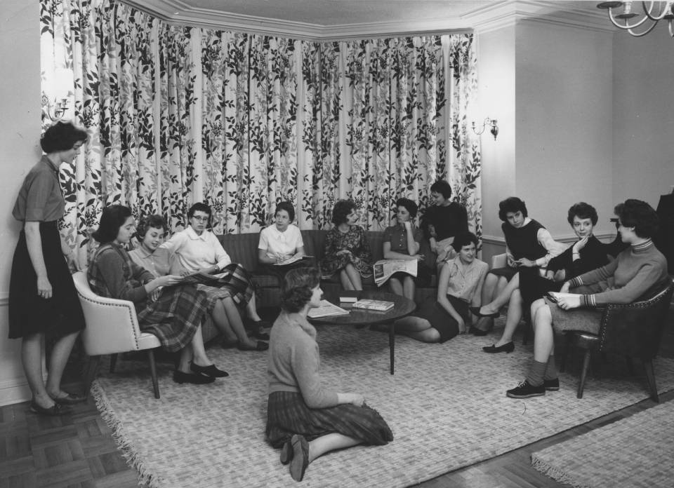 About thirteen young women sitting in a semi-circle.