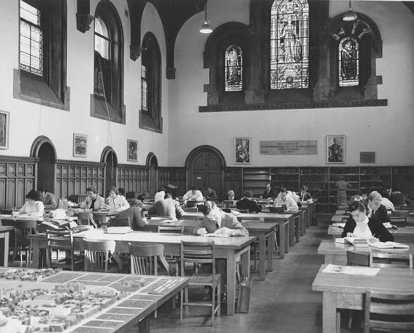 Students reading at tables and desks, with stained glass windows above