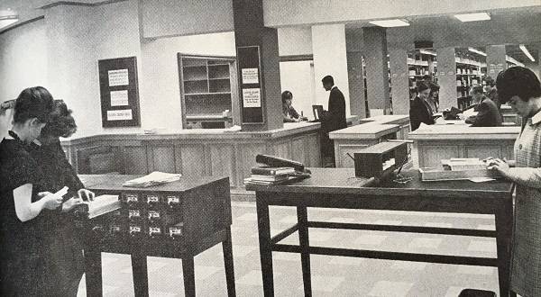 women looking in card catalogue, with two library service desks in background