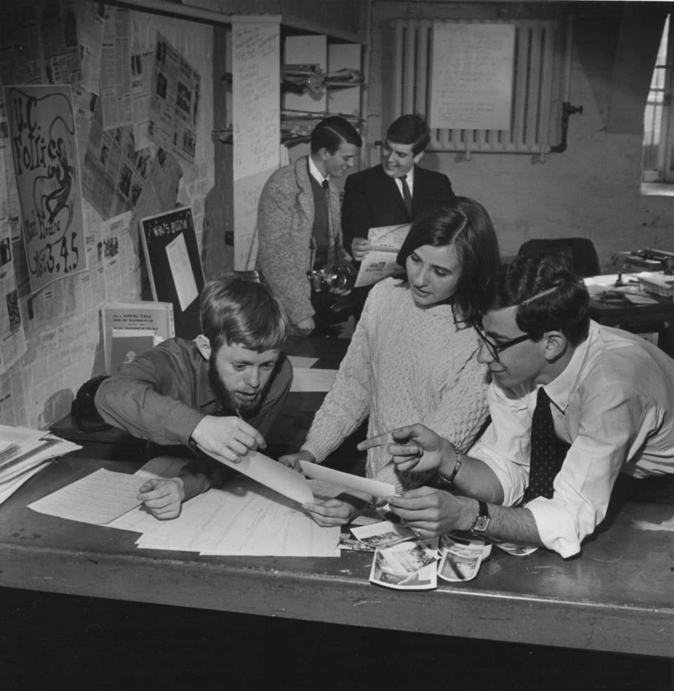 four men and one woman working on a magazine