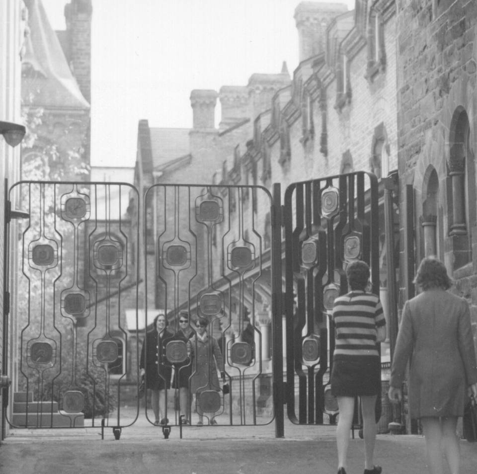five women about to enter or exit the University College quadrangle through a gate