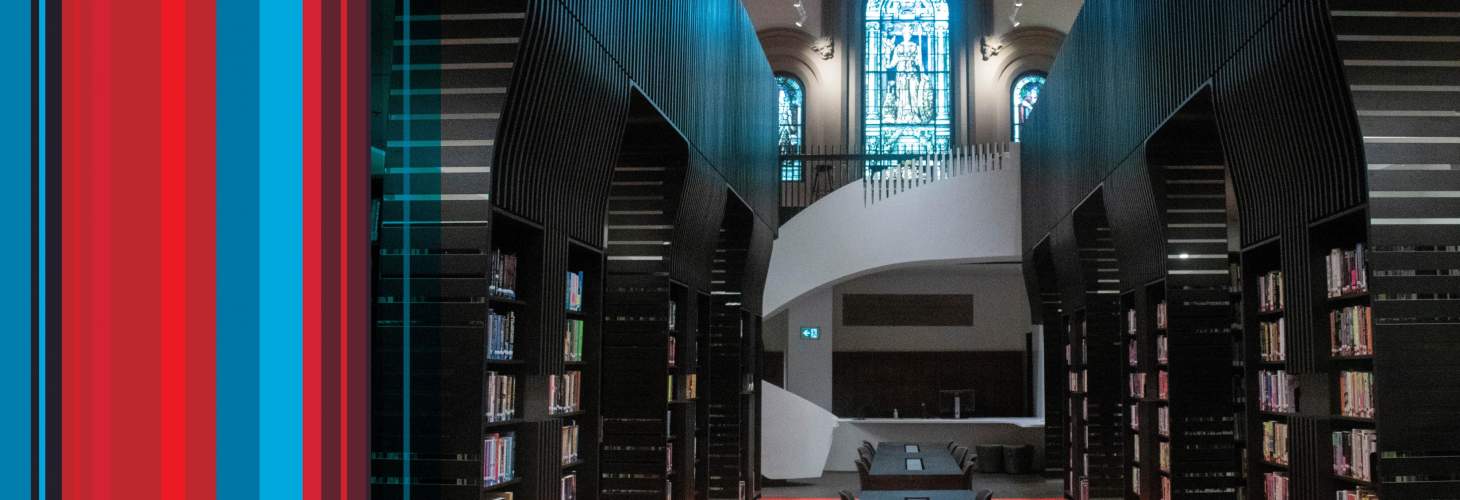 Interior of UC Library with large black bookshelves and white spiral staircase
