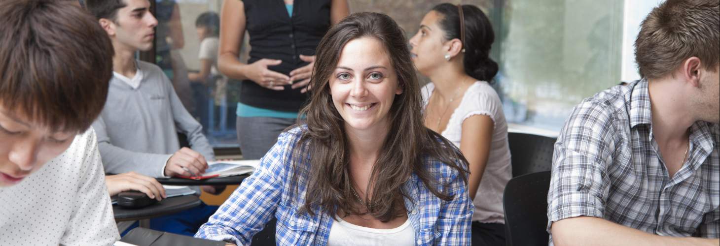 Smiling student along with other students in a classroom environment 