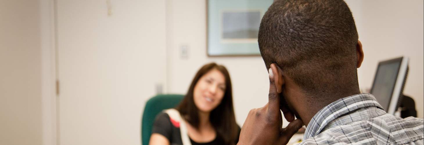 Student meeting with his academic advisor in her office 