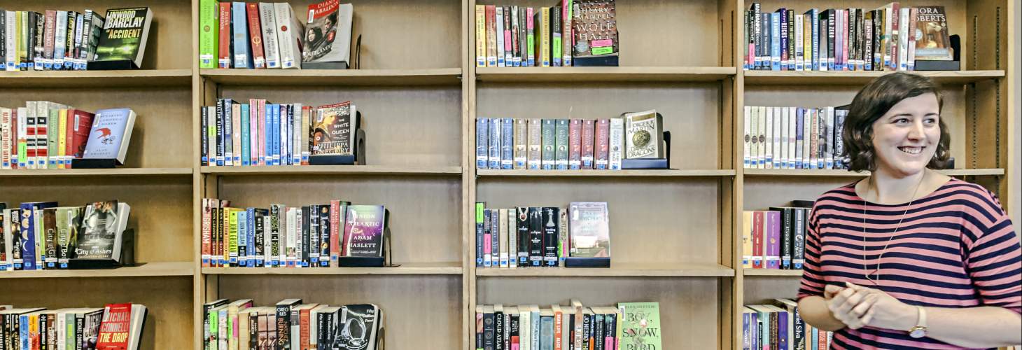 smiling staff member in front of shelves of books