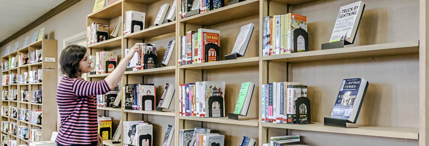 Woman browsing bookshelves containing bestsellers