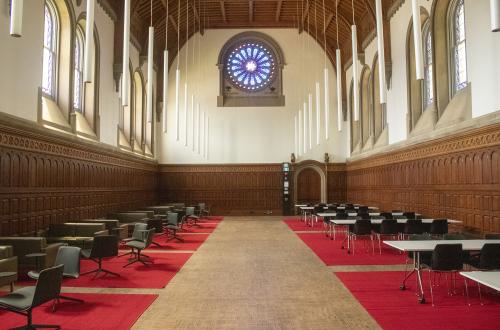 Large gothic hall with red carpets, stained glass, and pendulum lighting