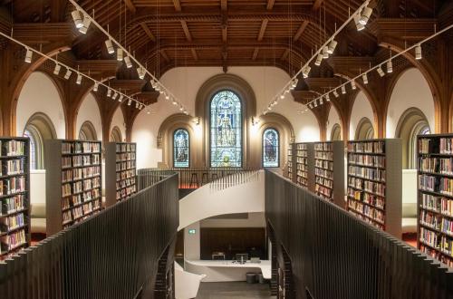 Large library with wooden ceiling, stained glass, and spiral staircase