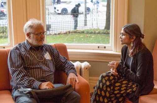 An alumni mentor and student mentee sit across from each other on a couch, talking