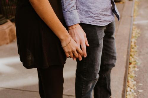 Two people holding hands on a city street