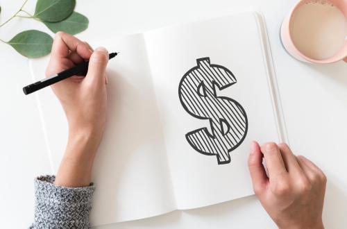 Left-handed student drawing a money sign in a notebook