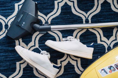 pair of sneakers beside vacuum cleaner