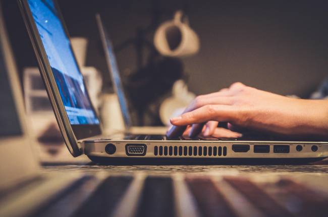 person using silver laptop on desk