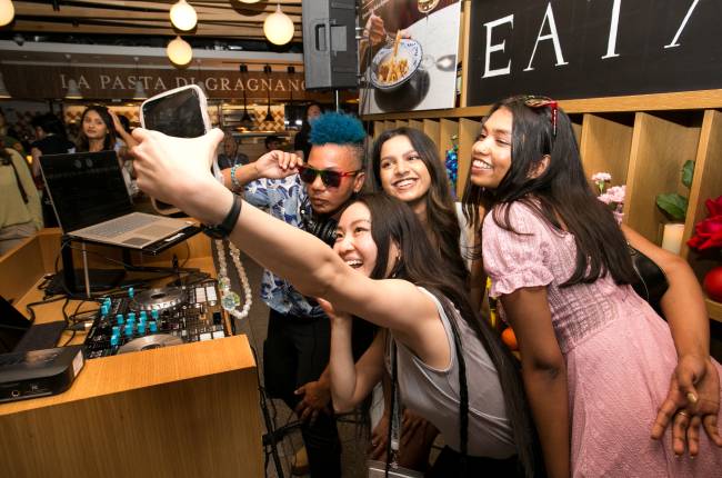 A group of young people pose as one takes a selfie of them at a party