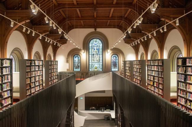 Large library with wooden ceiling, stained glass, and spiral staircase