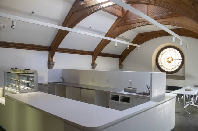 Empty cafe with white countertops, seating, and stained glass window