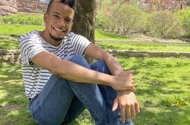 Student in striped shirt sitting underneath a cherry tree