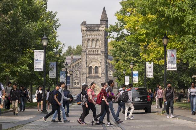 Group of student walking across front entrance of U of T with University College in the background