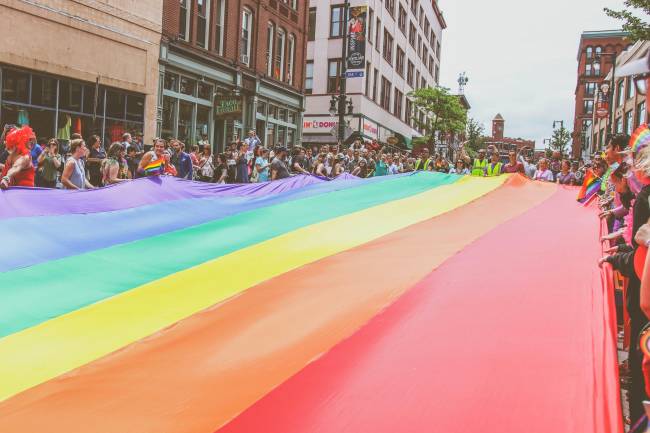 Pride Parade crowd holding street-wide rainbow flag