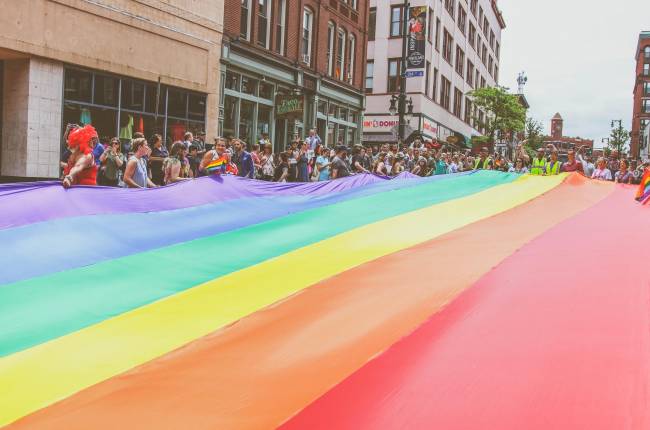 Pride Parade crowd holding street-wide rainbow flag