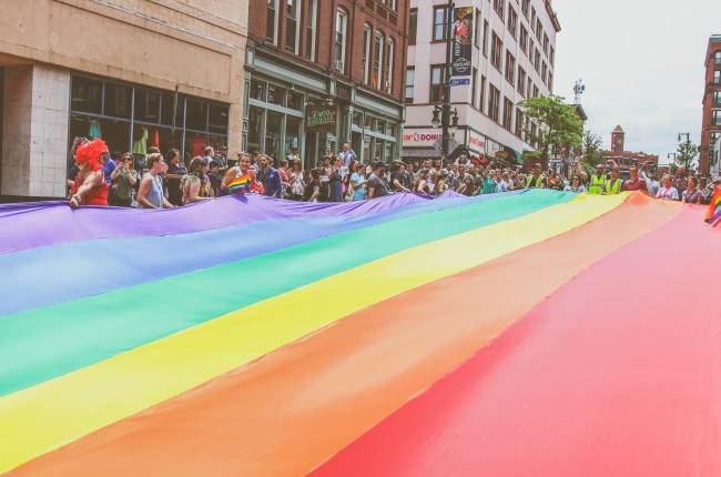 Pride Parade crowd holding street-wide rainbow flag