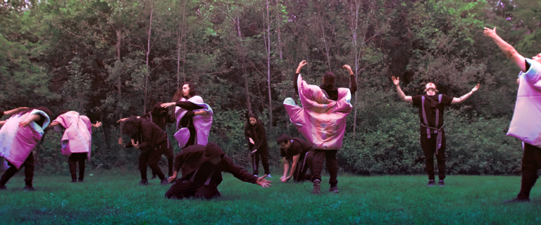 A group of people doing performance art in forest
