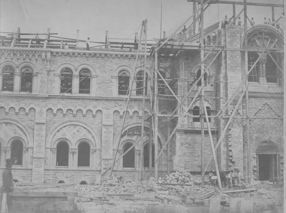 University College exterior under construction with scaffolding and workers