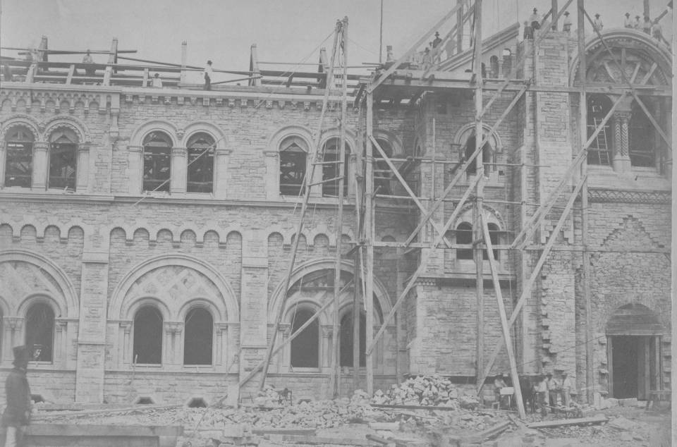 University College exterior under construction with scaffolding and workers