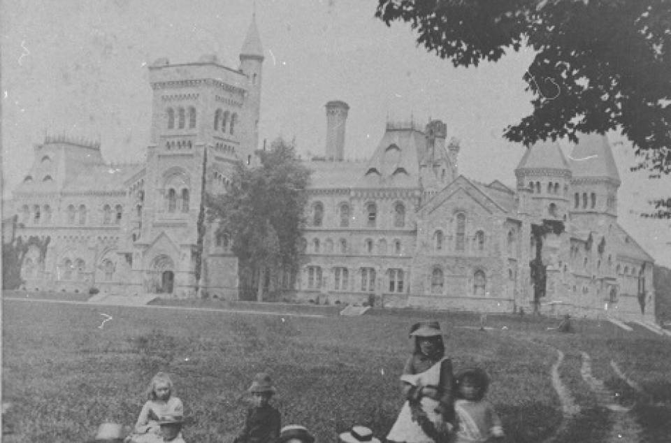 Eight children on grass with University College in background