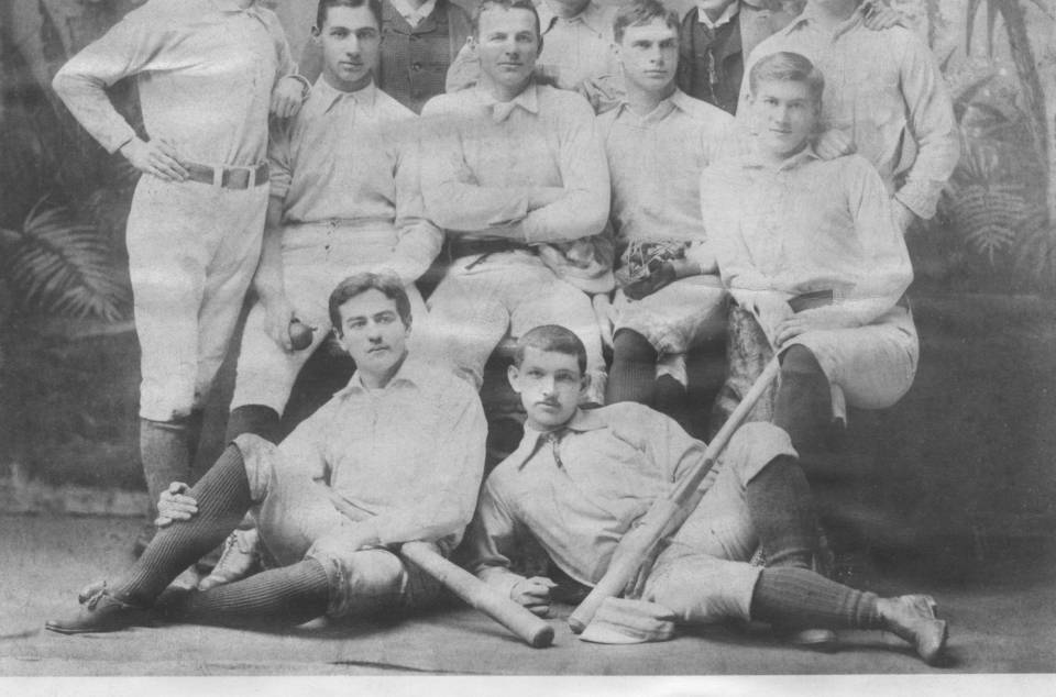 nine men in baseball uniforms and two men in suits