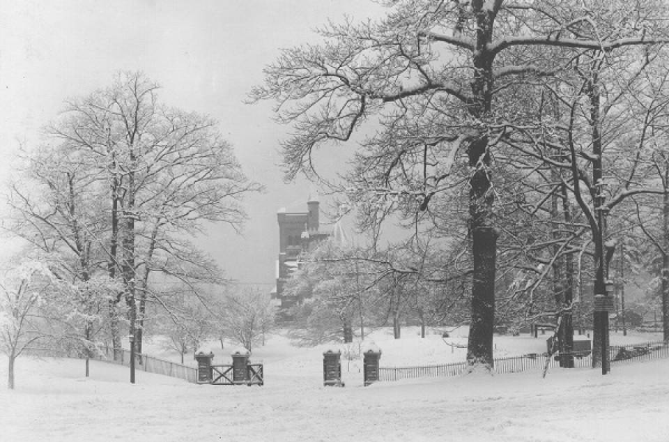 Gates and snowy park with University College in distance