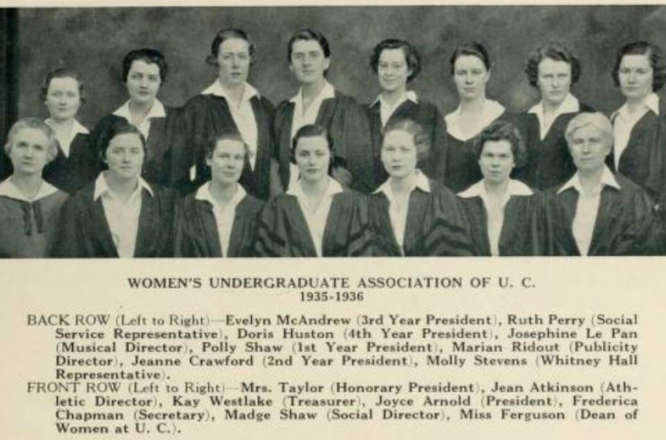 Thirteen young women in academic robes with two older women