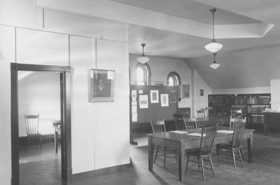 room containing tables, chairs, and bookshelves