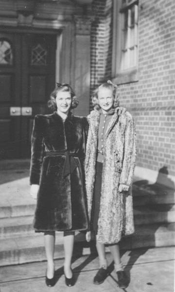 two young women in coats, with Whitney Hall behind them