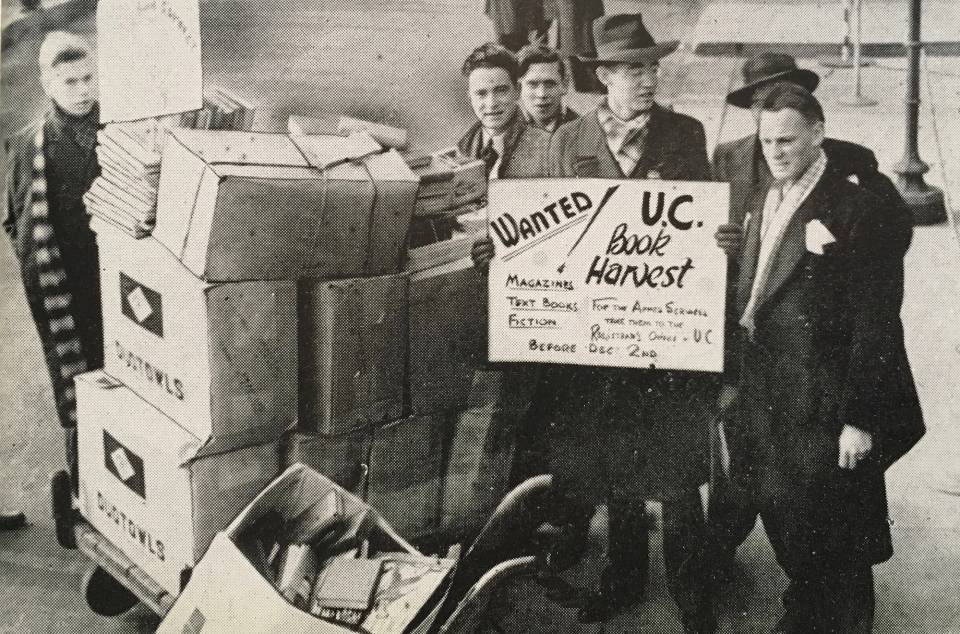 Six men with boxes of books and magazines, with a sign that says "U.C. Book Harvest for the Armed Services"