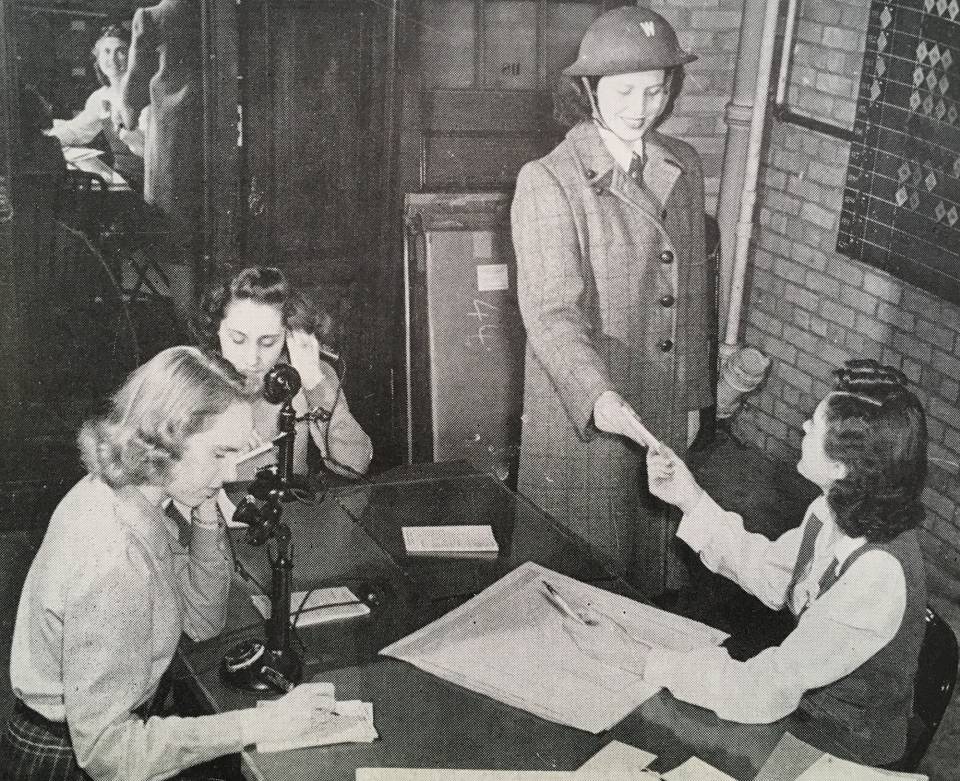 Six young women working, two of whom are on the telephone.