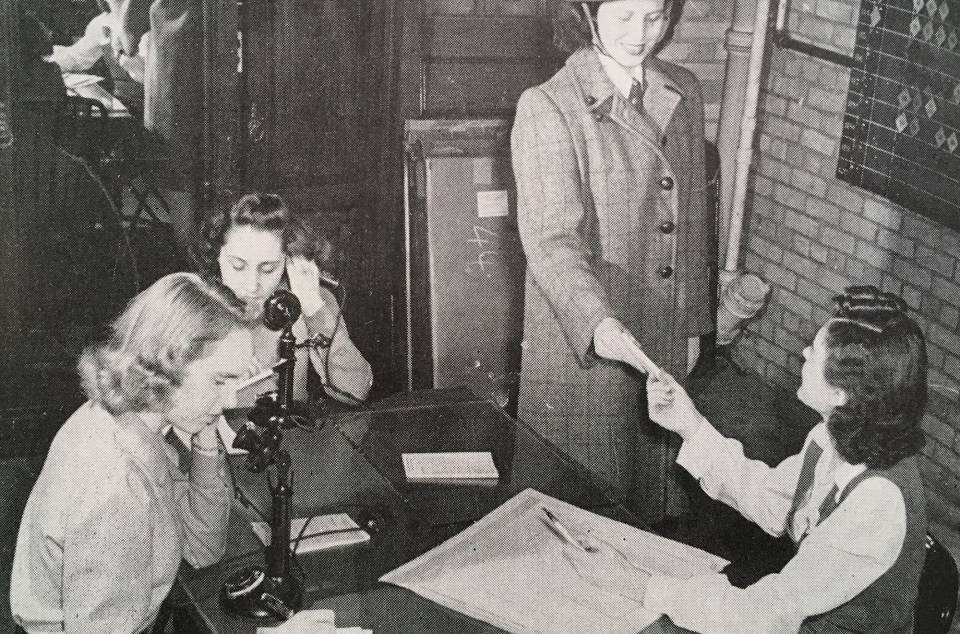 Six young women working, two of whom are on the telephone.