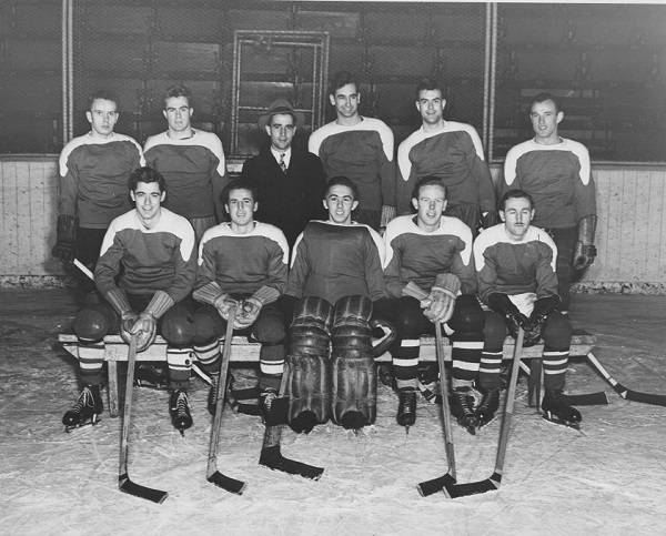 Ten men in hockey uniforms and one man in suit and tie